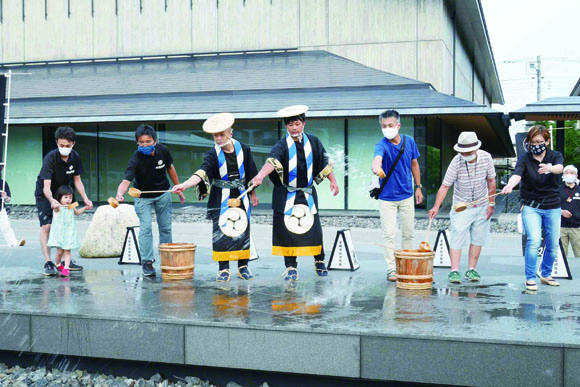 人形博物館を背景に打ち水